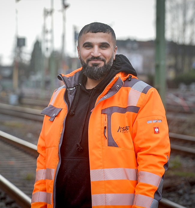 Sehmus Baydag, Geschäftsführer eines Ingenieurbüros aus Dortmund zeigt sich mit orange-strahlender Arbeitskleidung auf der Baustelle.